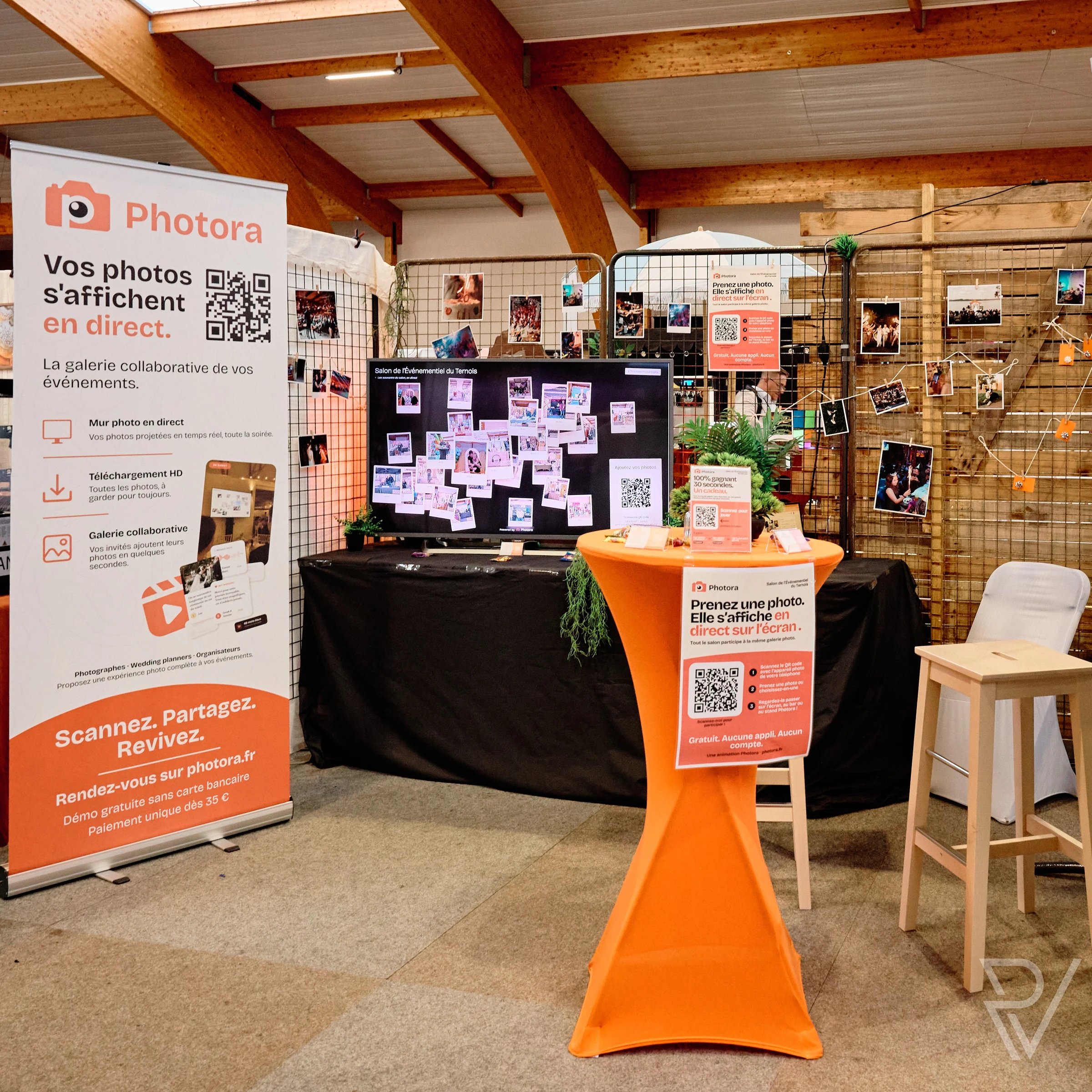 Stand Photora au salon : kakémono, écran du Mur Photo en Direct couvert de photos du salon et mange-debout avec l'affiche QR code