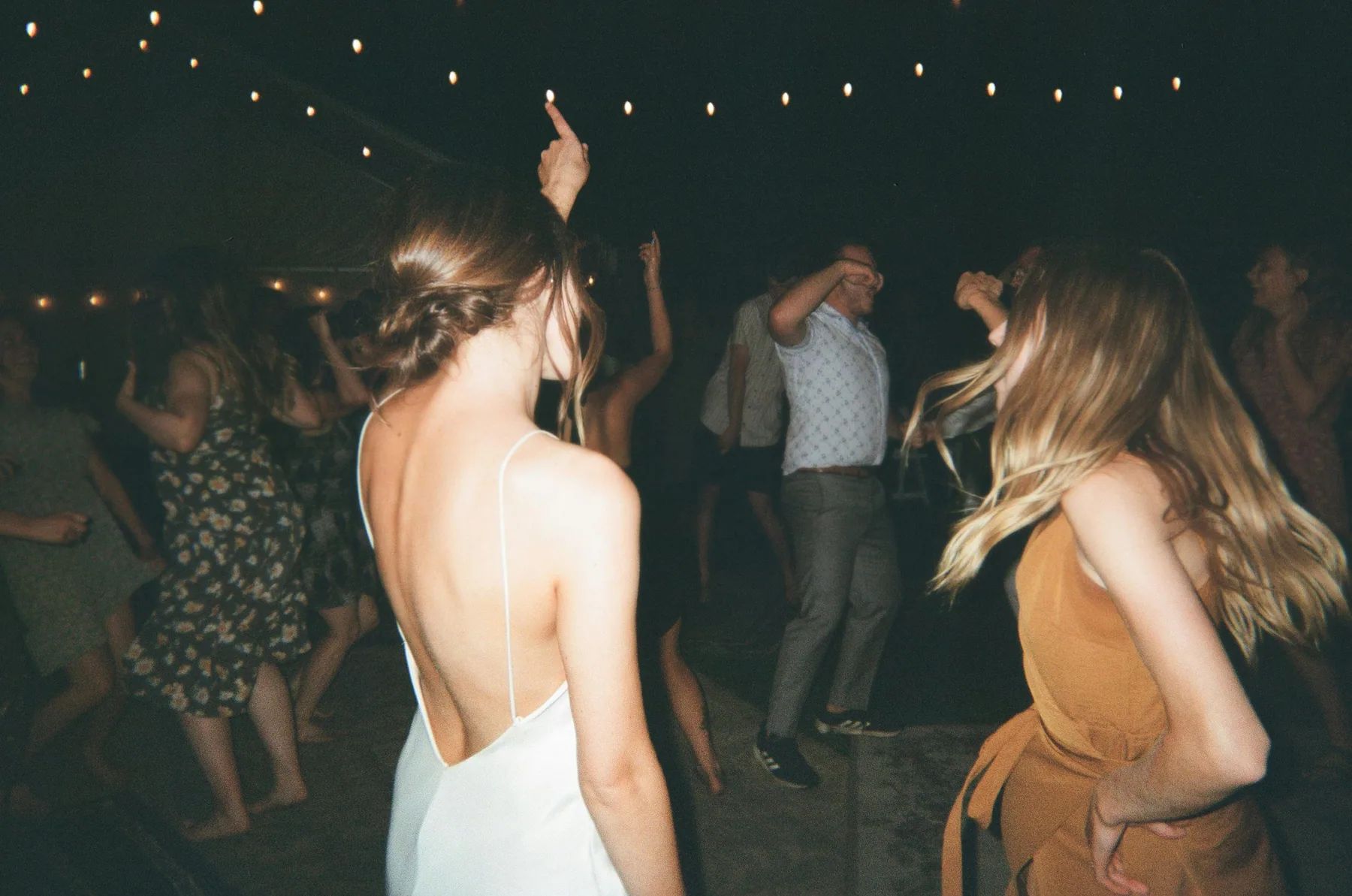 Invités dansant pendant la soirée de mariage, sous les guirlandes lumineuses