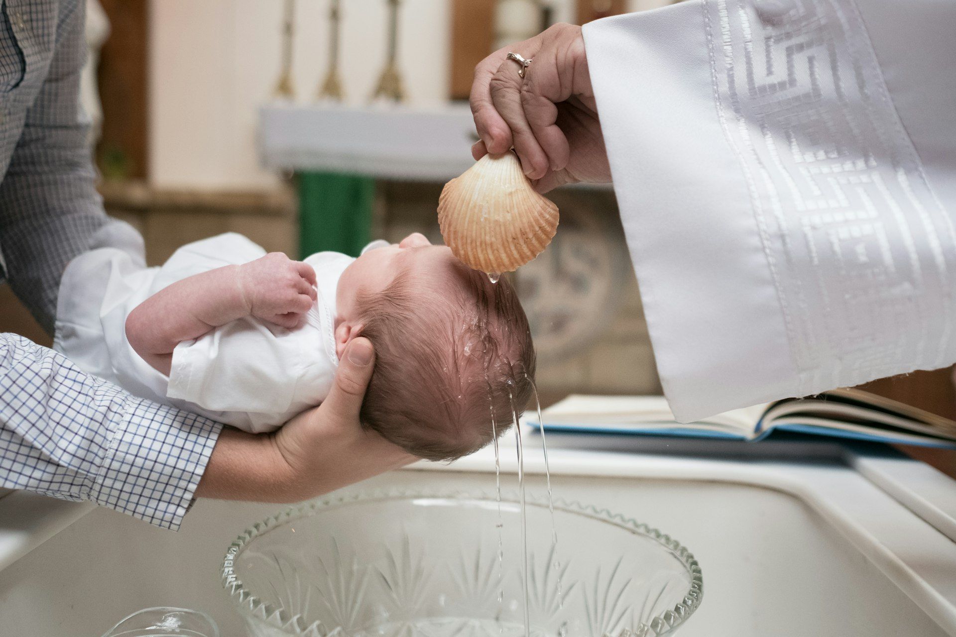 Prêtre versant l'eau du baptême sur le front d'un nourrisson pendant la cérémonie